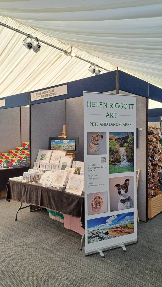 Helen Riggott Art stand inside a show marquee, with a banner and a table of mounted pictures